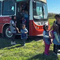 Chicos de jardín bajan de un micro escolar en el campo